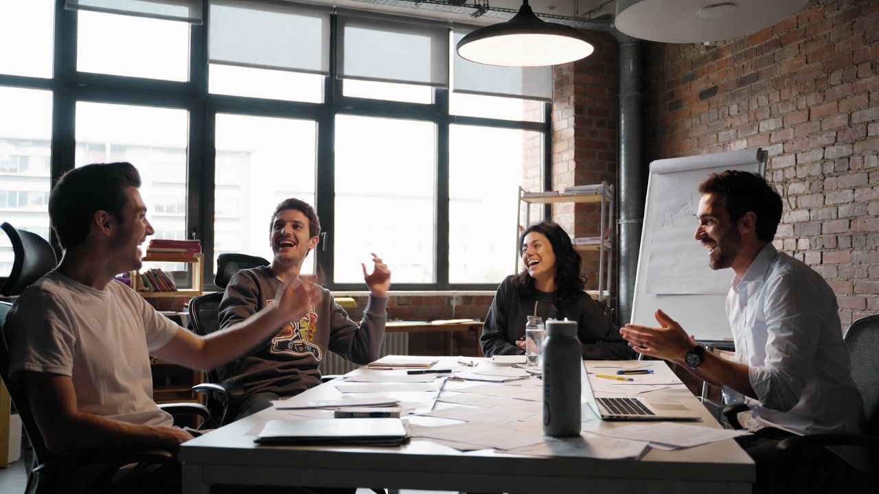 Agency team laughing around a table covered in scripts and notes